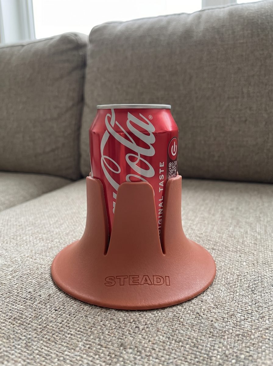 A can standing in a terracotta Steadi on a grey sofa cushion.
